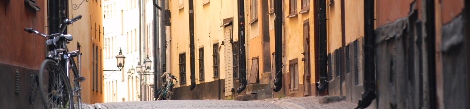 Gatubild Gamla stan i Stockholm, hus med många stuprör, två cyklar lutade mot husväggarna
