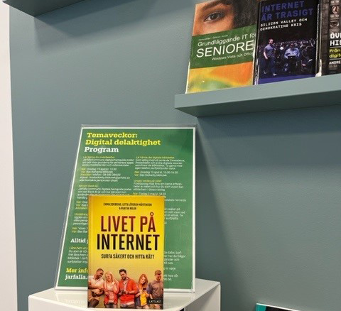 Skyltning på biblioteket i Barkarby. En bok med titeln Livet på internet och en affisch med reklam för temavecka om digital delaktighet.
